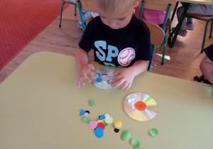 Chłopiec nakleja kolorowe kropki z papieru
